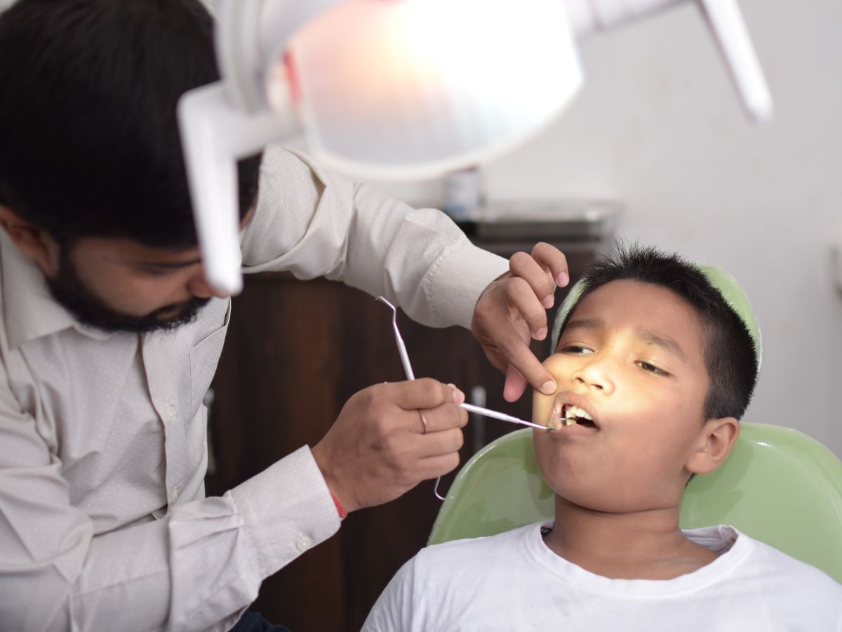 A dentist examining a young patient in the dental chair
