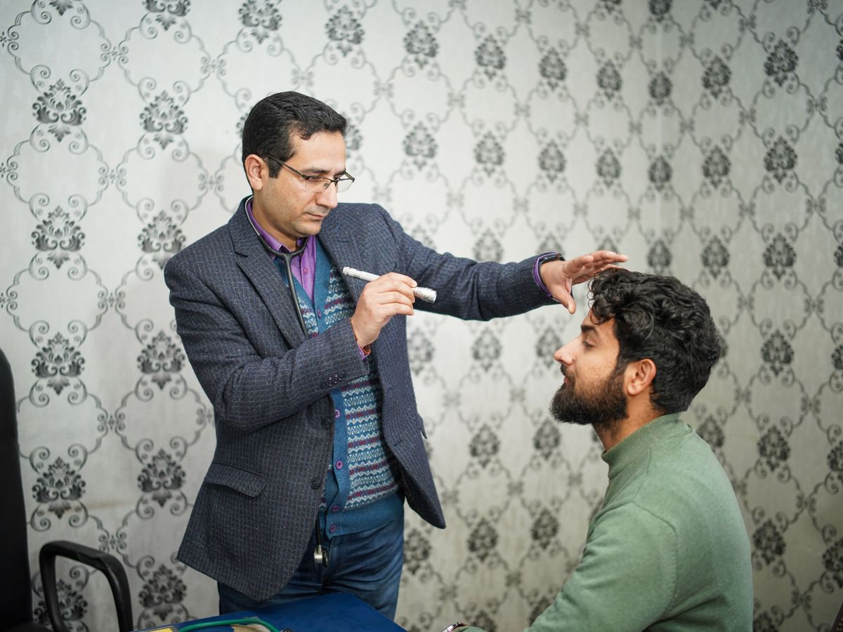 An eye doctor examining a male patient's eyes in the clinic